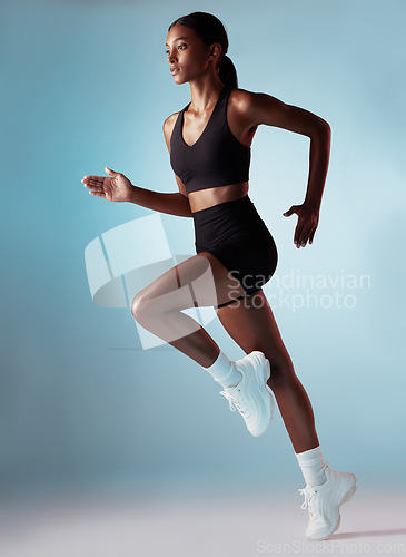 Image of Fitness, health and black woman running in studio with blue background. Sports, exercise and form, motivation for strong runner cardio training for a marathon or race, workout for woman from Jamaica.