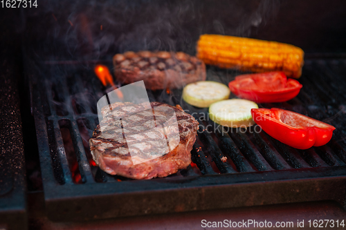 Image of Beef steaks on the grill with flames