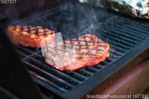 Image of Beef steaks on the grill with flames