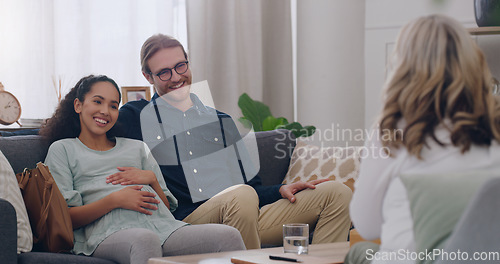 Image of Happy, counseling and couple with a psychologist in an office for a therapy session together. Happiness, pregnant woman and her husband talking to a professional family therapist with a smile.