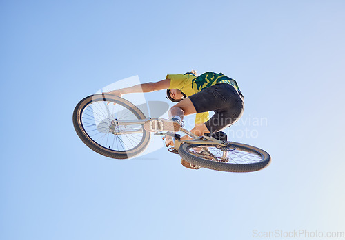 Image of Bicycle, cyclist man and jump of adrenaline junkie from below riding in a competition with copyspace. Extreme sport, bicycle and cycling man stunt while on bike against a blue sky background