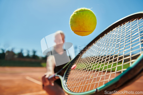 Image of Close up photo of a young girl showing professional tennis skills in a competitive match on a sunny day, surrounded by the modern aesthetics of a tennis court.