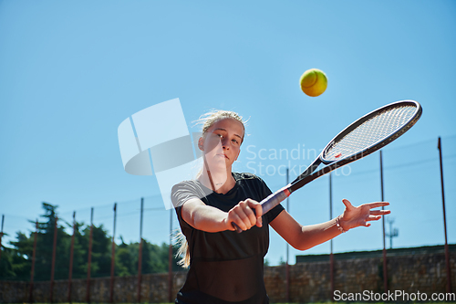 Image of A young girl showing professional tennis skills in a competitive match on a sunny day, surrounded by the modern aesthetics of a tennis court.