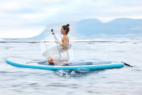 Image of Paddle board, sea and fitness with a sports woman floating on water in nature for wellness or exercise. Earth, training and travel with a female athlete on a paddleboard while on vacation for travel