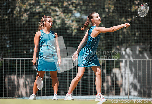 Image of Badminton, sports and women with a serve on an outdoor court busy with fitness and exercise. People training, cardio and athlete workout of sport student teamwork and collaboration together