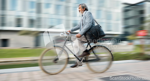 Image of Bike, commute and blurred motion with a mature man in business cycling in the city on his morning trip into work. Road, travel and bicycle with a senior male employee riding on a street in town