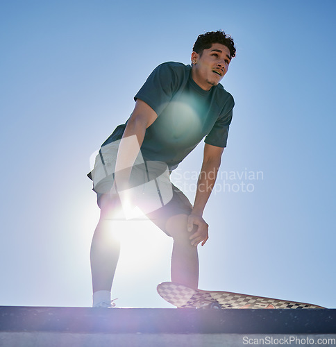 Image of Young man, skateboard and freedom on blue sky lens flare at urban skate park, city and relaxing summer for training, outdoor action and sports hobby in USA. Skater ready for action jump risk off ramp