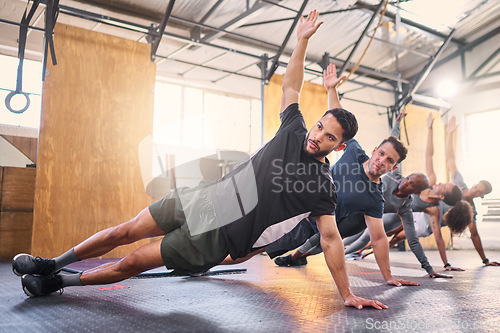 Image of Strong man, personal trainer and group training with side plank exercise, workout and fitness in gym club. Bodybuilder coach teaching sports class, bodyweight wellness challenge and strong people