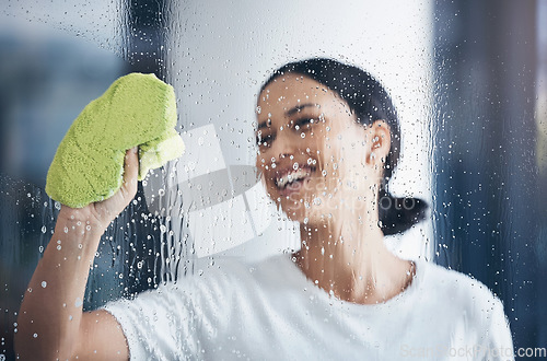 Image of Cleaning, washing window and woman with cloth in hand to wipe water, detergent and cleaning products. Hygiene, housekeeping and happy girl doing housework, chores and and wash or clean clear glass