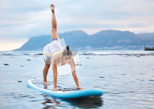 Image of Surfer, flexible and woman on surfboard at a beach training, workout and full body yoga exercise on water in nature. Ocean, surfing and sports girl in a downward dog pose with balance and fitness