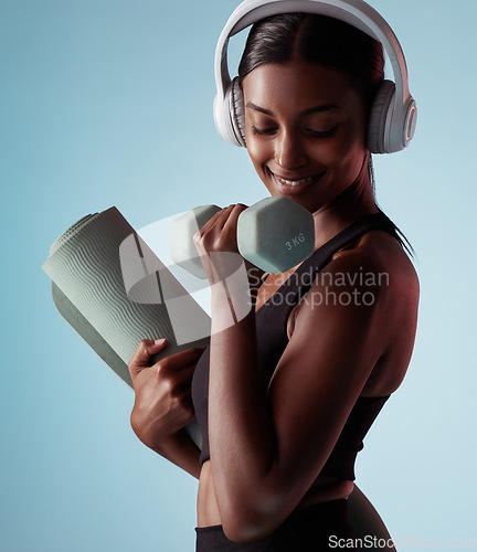 Image of Yoga, dumbbell and woman in studio training strong biceps in exercise with headphones for music streaming. Fitness, healthy and happy girl listening to audio, radio and lifting weights for arm power