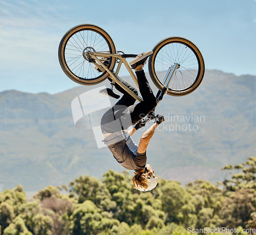 Image of Mountain bike, man and upside down air jump, action and bicycle stunt, challenge and adventure, freedom or dynamic risk in sky. Biker athlete, sports adrenaline and energy in outdoor competition show