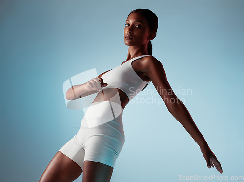 Image of Fitness, body and stretching woman in studio portrait with workout clothes on blue mock up for marketing or advertising space. Young black woman or fashion model dancing and training with mockup