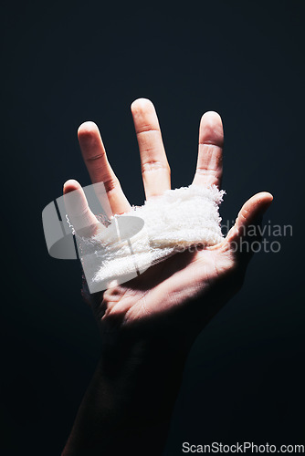 Image of Bandage, black and hand palm of man with medical injury pain, first aid care and hurt from mma fight, boxing or crime violence. Shadow light, dark trauma wound and sports boxer with injury spotlight