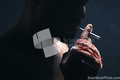 Image of Injury, cigarette and blood bandage on hand of kickboxing man in studio for shadow, art deco and bad habits background. Male champion boxer smoking after fighting in MMA violence sports competition