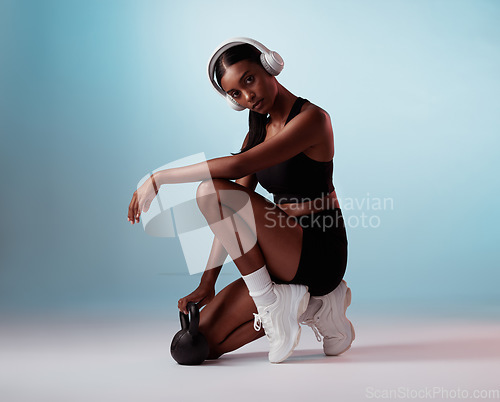 Image of Headphones, fitness and kettlebell black woman in studio portrait for workout music, body training or wellness audio. Gym, exercise and health girl in sports fashion marketing or advertising mock up