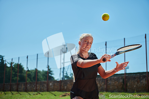 Image of A young girl showing professional tennis skills in a competitive match on a sunny day, surrounded by the modern aesthetics of a tennis court.