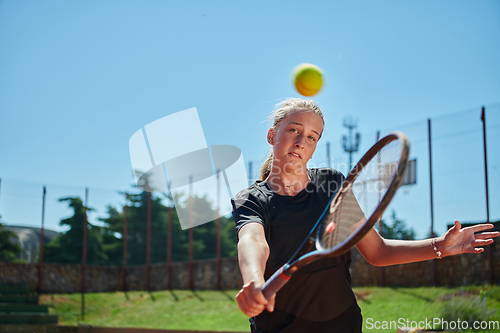 Image of Close up photo of a young girl showing professional tennis skills in a competitive match on a sunny day, surrounded by the modern aesthetics of a tennis court.