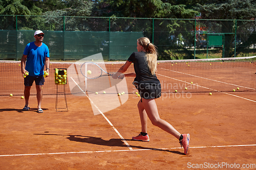 Image of A professional tennis player and her coach training on a sunny day at the tennis court. Training and preparation of a professional tennis player