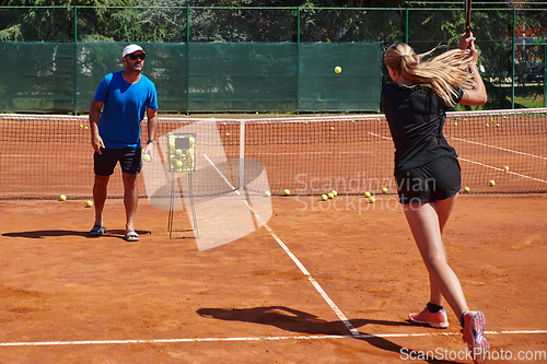 Image of A professional tennis player and her coach training on a sunny day at the tennis court. Training and preparation of a professional tennis player