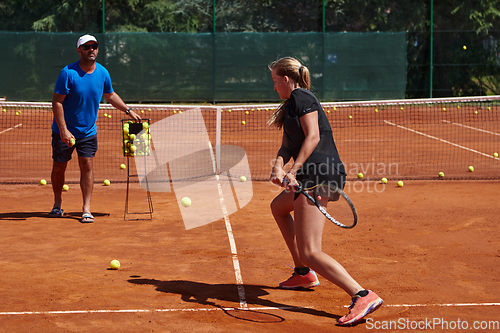 Image of A professional tennis player and her coach training on a sunny day at the tennis court. Training and preparation of a professional tennis player