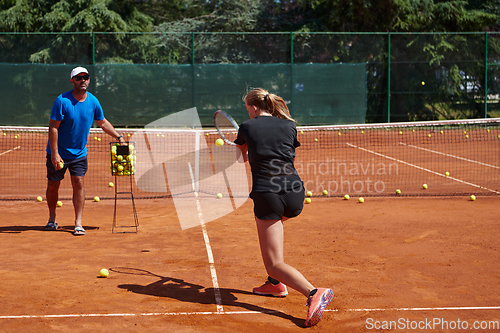 Image of A professional tennis player and her coach training on a sunny day at the tennis court. Training and preparation of a professional tennis player