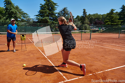 Image of A professional tennis player and her coach training on a sunny day at the tennis court. Training and preparation of a professional tennis player