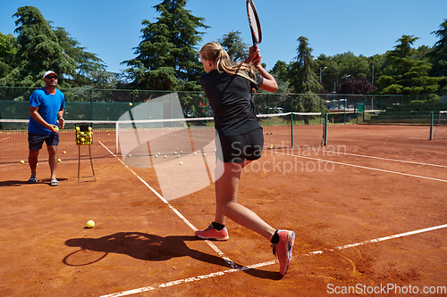 Image of A professional tennis player and her coach training on a sunny day at the tennis court. Training and preparation of a professional tennis player