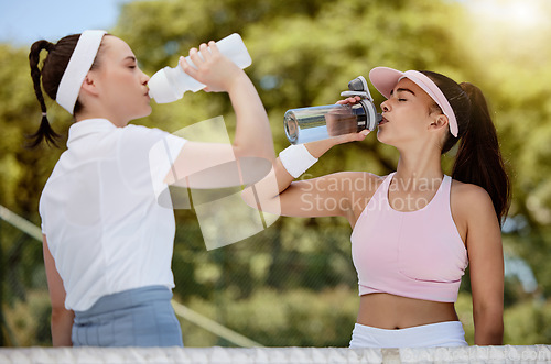 Image of Tennis, fitness and water, women drinking from bottle on court in hot summer sun at match. Sports exercise, healthy friendship and training workout, girl friends drinking water at competition or game