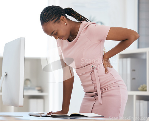 Image of Back pain, bad posture and strain with a black woman in business suffering while working at her desk in the office. Anatomy, spine and cramp with a female employee struggling with backache at work