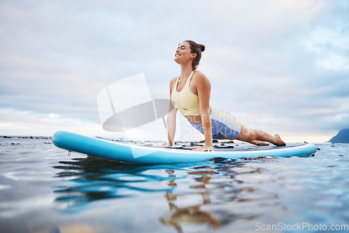 Image of Ocean, surfing and woman doing yoga on surfboard in morning, ready to surf and relax. Wellness, water sports and girl doing stretching exercise on paddle in sea, enjoy calm, waves and peace in nature