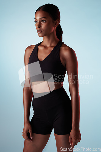 Image of Fitness, training and a woman serious about health on blue studio background. Thinking, focus and concentration on exercise and motivation to workout with sport model with healthy, fit and slim body