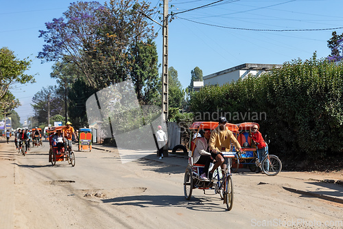 Image of Traditional rickshaw bicycle with Malagasy people on the street of Antsirabe, one of the ways to earn money. Everyday life on the street of Madagascar.