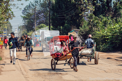 Image of Traditional rickshaw bicycle with Malagasy people on the street of Antsirabe, one of the ways to earn money. Everyday life on the street of Madagascar.