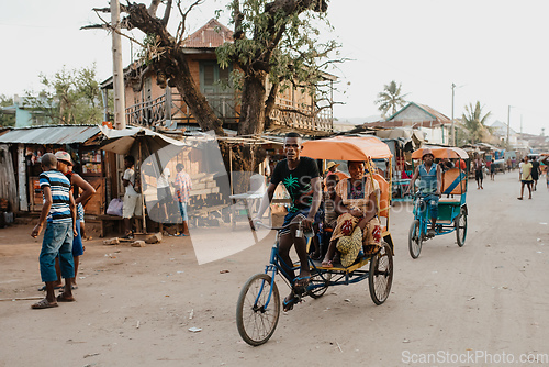 Image of Traditional rickshaw bicycle with Malagasy people on the street of Miandrivazo, one of the ways to earn money. Everyday life on the street of Madagascar.