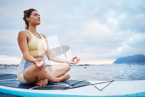 Image of Meditation, surf and sea with a woman on a surfboard floating out in nature with a cloudscape and mockup. Yoga, ocean and zen with a young female meditating for health, wellness or balance outside