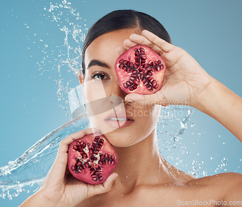 Image of Pomegranate, skincare and beauty woman with water splash in studio blue mock up for healthy, wellness and skin glow advertising. Young woman with vitamin c fruits for facial product marketing mockup