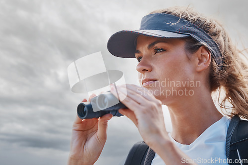 Image of Woman, binoculars and hiking in nature, travel or outdoors vacation, holiday or trip in Canada. Freedom, cloudy sky and female on adventure, sightseeing or trekking and looking with field glasses.