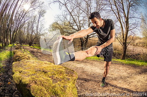 Image of Male runner stretching outdoors