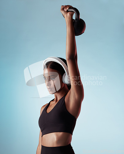 Image of Fitness, music and woman lifting a kettlebell in studio strength training, sports workout and full body exercise. Healthy, sports and Indian girl with strong arms streaming a podcast audio or radio