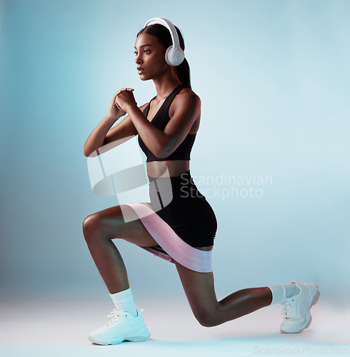 Image of Woman, music headphones or resistance band workout on blue background in studio for training, exercise or gym. Personal trainer, person or fitness model with health goals, radio or motivation podcast
