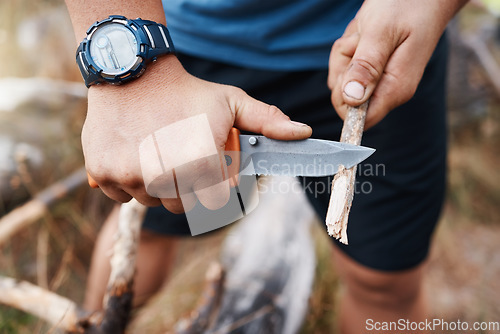 Image of Hands, knife and cutting with a hiking man carving a stick outdoor in nature while camping for adventure. Wood, weapon and tool with a male camper slicing a twig in the mountains for survival