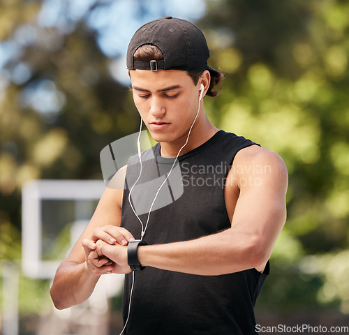Image of Fitness, smartwatch and sports man listening to music with earphones and gadget while outdoor for exercise, fitness and training workout. Male with watch to monitor progress, cardio and performance