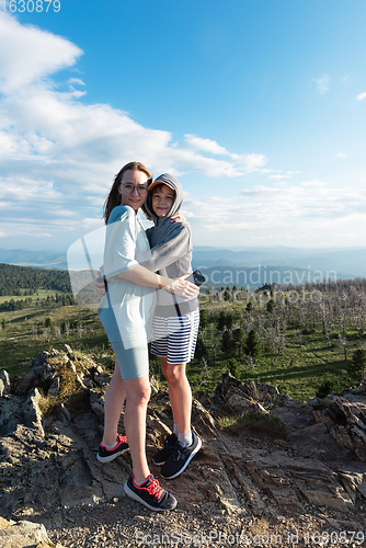 Image of A child embraces mom in the mountain trip