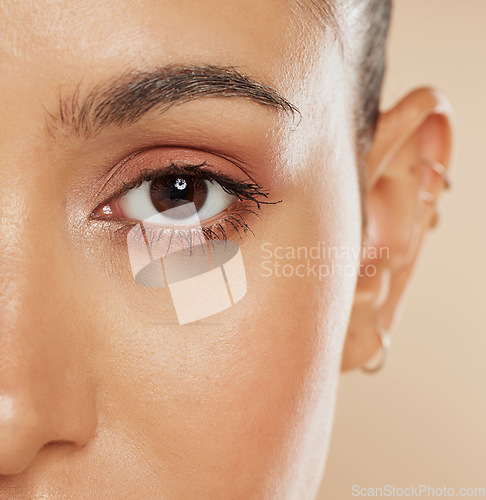 Image of Eye, vision and beauty with a model woman closeup in studio on a beige background for eyecare or skincare. Zoom, cosmetics and wellness with a female posing to show her eyelash, eyebrow or pupil