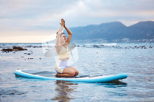 Image of Yoga, beach and woman in the water for meditation, training of mind and spiritual wellness. Peace, relax and girl with paddle board, zen and motivation while surfing on a surfboard in sea in summer