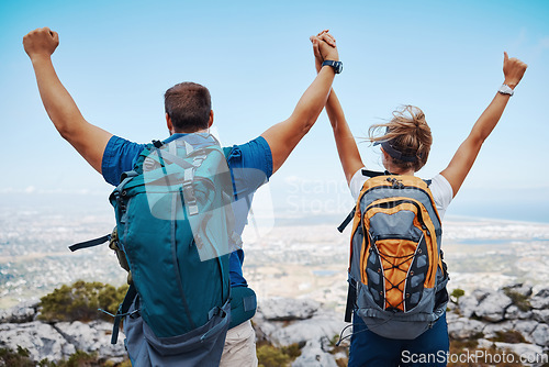 Image of Success, hiking and couple holding hands on a mountain top in celebration with freedom and support outdoors. Nature, goals and healthy woman enjoys a lovely fitness milestone achievement with partner