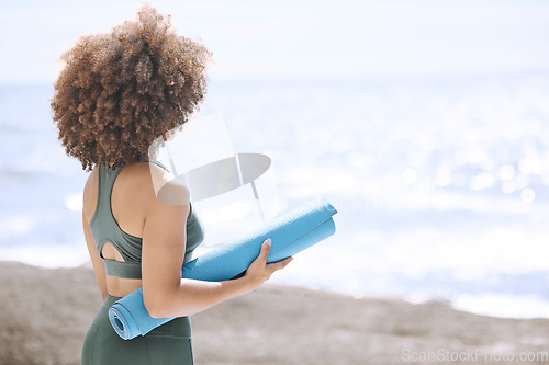 Image of Black woman, yoga mat and enjoying ocean and view before zen, peaceful and relaxing exercise. A yogi and woman ready to meditate at beach. Nature, african american girl and meditation by sea