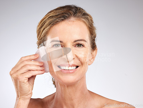 Image of Face, beauty and senior woman with stone for facial massage on gray studio background. Health, skincare and elderly female model from Canada with rose quartz guasha for anti aging or smooth wrinkles
