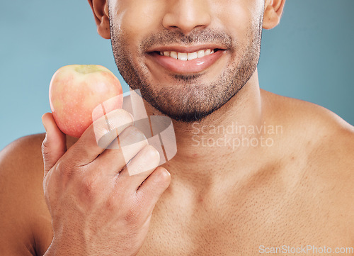 Image of Face, skincare and man with apple for health, vitamin c and nutrition on blue studio background. Wellness, healthy lifestyle or bearded model holding fruit for minerals, natural skin or facial care